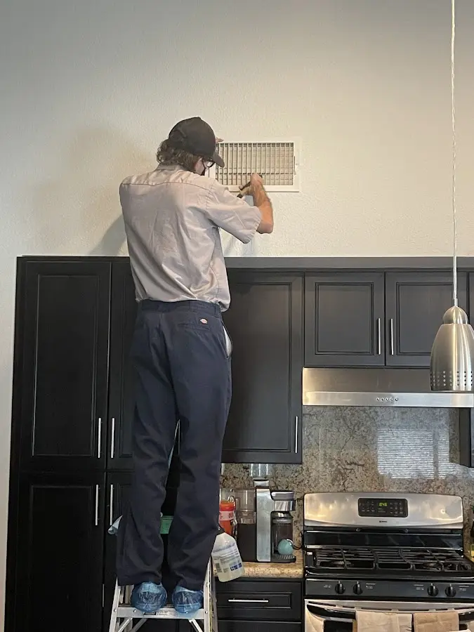 Technician inspecting an air vent during HVAC service in La Junta